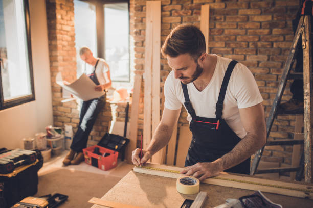 operaio che effettua misurazioni su un pezzo di legno in cantiere. - carpenter home addition manual worker construction foto e immagini stock