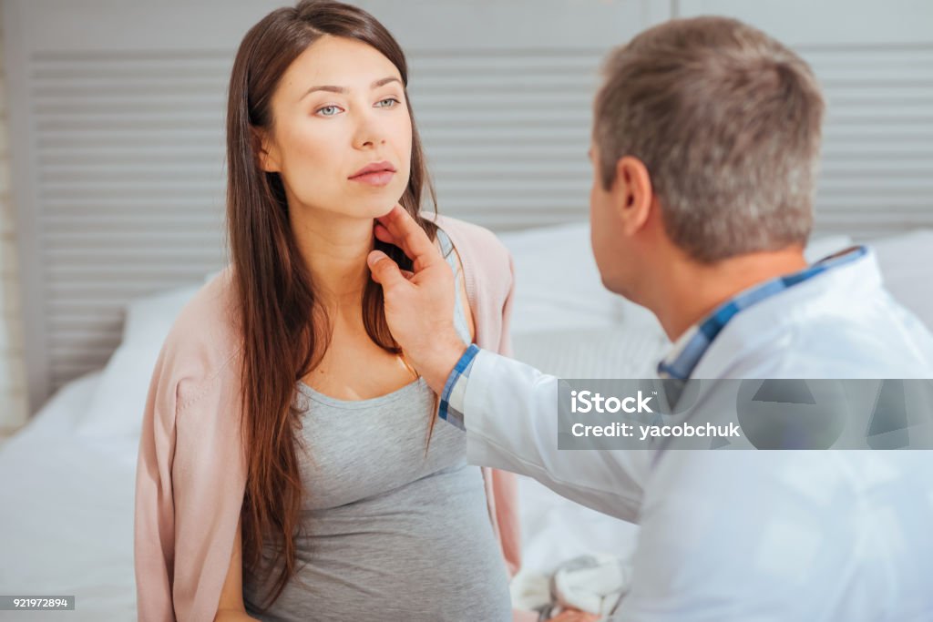 Beautiful pregnant woman visiting doctor Health is of utmost importance. Selective focus on a young brunette sitting in a clinic during her monthly appointment with doctor. Abdomen Stock Photo