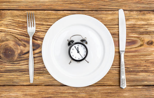 istock Alarm clock with fork, knife and plate on the table. Top view. Time to eat. 921973510