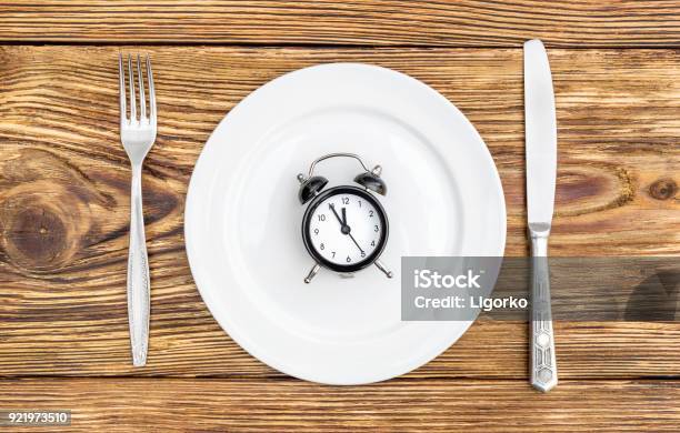 Alarm Clock With Fork Knife And Plate On The Table Top View Time To Eat Stock Photo - Download Image Now