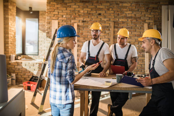 istock Young female architect talking to three construction workers during home improvement. 921976432
