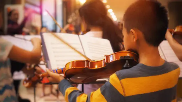 Photo of Young violinist practicing with orchestra band.