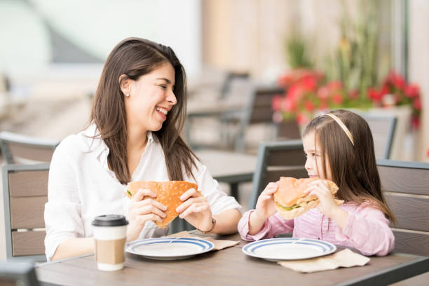 istock Smiling mother and daughter eating a burger 921980798
