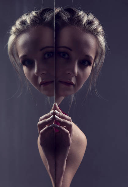 Portrait close-up of a beautiful blond woman looking around the corner of a mirror in artistic conversion stock photo