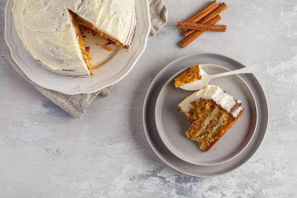 Homemade vegan carrot cake with white cream (cream cheese) on a gray background, top view, copy space. Festive dessert concept. Piece of carrot homemade cake with white cream on a gray background. Festive dessert concept. carrot cake stock pictures, royalty-free photos & images