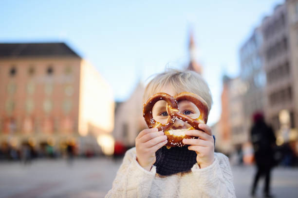 pouco turista segurando o pão tradicional da baviera chamado pretzel na prefeitura edifício histórico em munique, alemanha - nova prefeitura de munique - fotografias e filmes do acervo