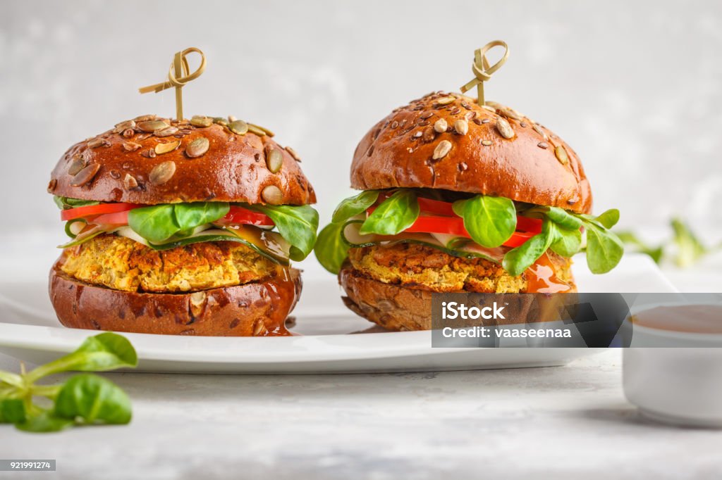Vegan lentils burgers with vegetables and curry sauce on white dish. Healthy vegan food concept. Vegan lentils burgers with vegetables and curry sauce. Light background, copy space. Healthy vegan food concept. Burger Stock Photo