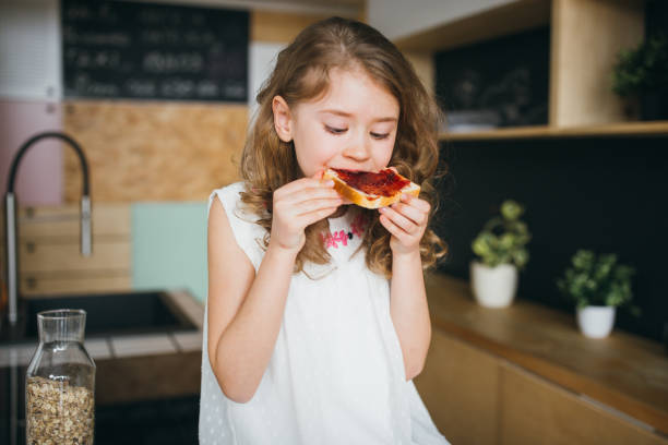 petite fille prenant le petit déjeuner - butter bread breakfast table photos et images de collection