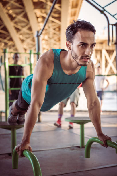 istock Latino guy doing push ups on hot summer day outdoors under the bridge 921996402