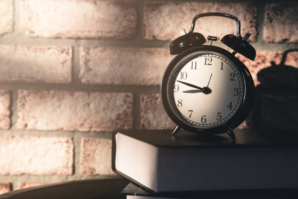 istock black alarm clock on wooden table and brick background with free copy space for yor creativity ideas text 921997324