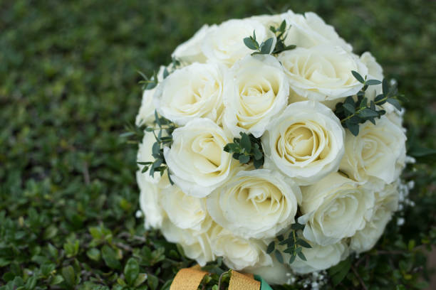 istock White rose flower bouquet in bundle shape for bridal in wedding ceremony on green grass 921997912