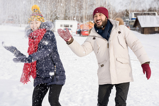 Portrait of young Asian couple having fun in snow enjoying nice winter days outdoors on ski resort