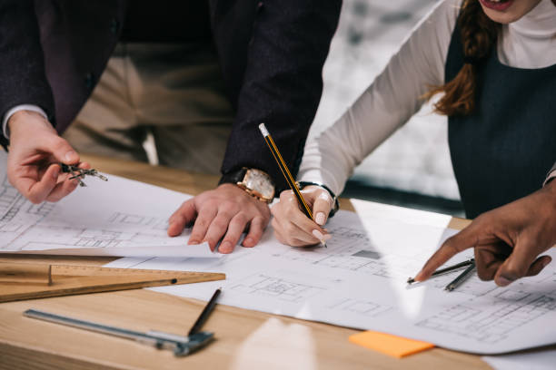 istock cropped view of multiethnic architects discussing and drawing building plans in office 922004974