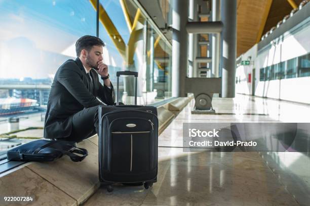 Young Businessman Upset At The Airport Waiting His Delayed Flight With Luggage Stock Photo - Download Image Now