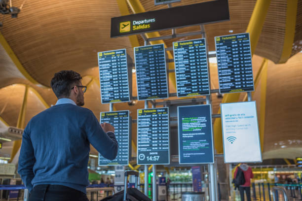 man checking his flight on the timetable display at the airport stock photo