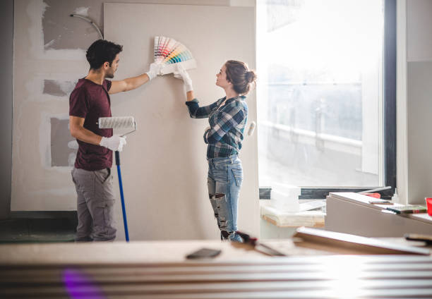 Young couple choosing the right color for their wall while renovating apartment. Young couple choosing the right color for their wall in new apartment. painting activity stock pictures, royalty-free photos & images