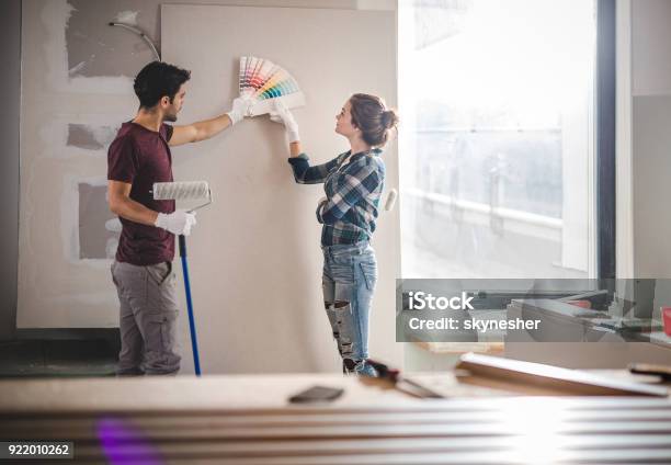 Young Couple Choosing The Right Color For Their Wall While Renovating Apartment Stock Photo - Download Image Now