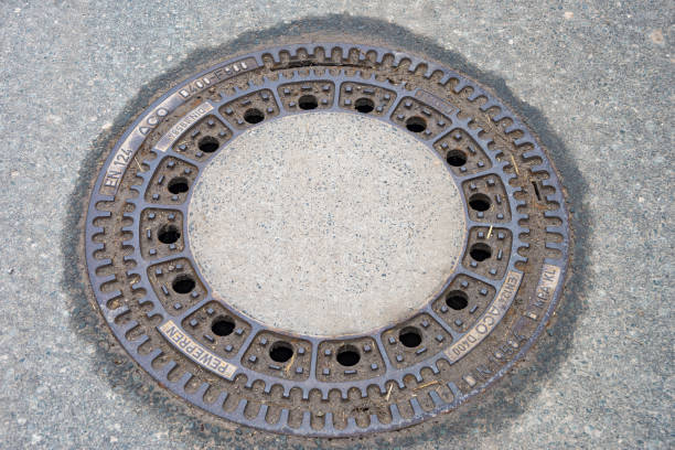 round manhole cover on the footpath - metal rusty rust textured imagens e fotografias de stock