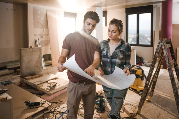 istock Young couple examining blueprints while being on construction site in their apartment. 922011170