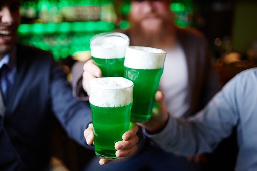 Three glasses of irish beer held by group of friendly men during toast