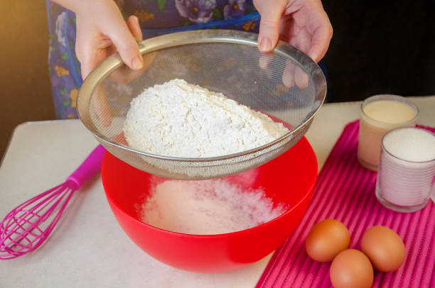 istock Baking Ingredients and Utensils for Cooking Sponge Cake. Process Cooking Sponge Cake. Woman Sifts the Flour Through a Sieve 922014500