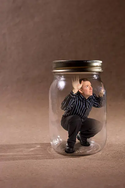 Photo of Man trapped in mason jar looking out (Concept Series)