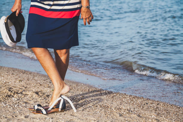 istock Woman walks along sandy beach with marine cap in hand 922023982