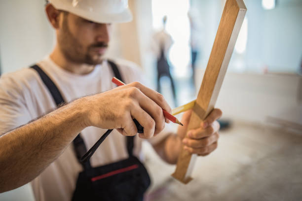 Close up of a carpenter using tape measure while working on a piece of wood during home improvement process.