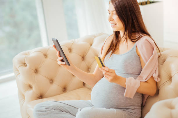istock Joyful parturient woman using the tablet and holding credit card 922032238
