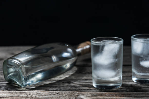 istock Vodka in shot glassesand bottle on rustic wood table black background 922033846