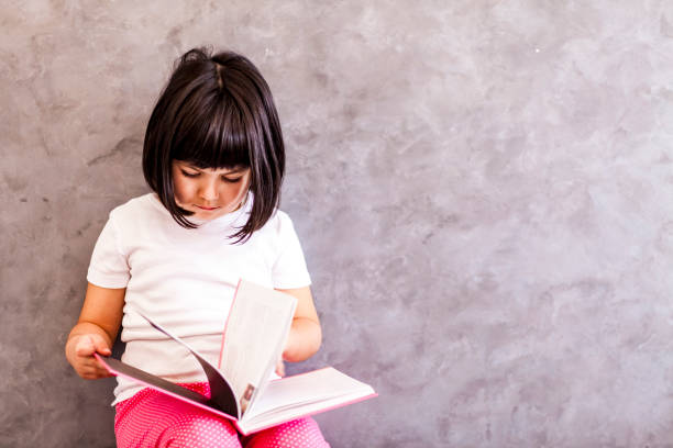 istock Little girl reading book by the wall 922039220