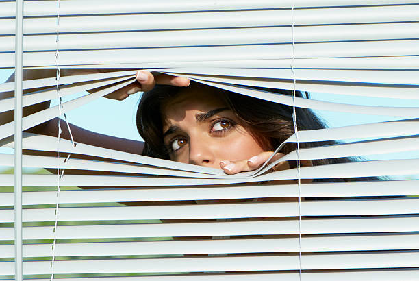 istock girl looking through the blinds 92204759
