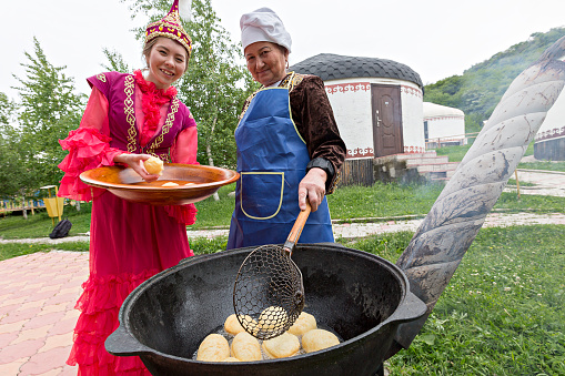 Almaty, Kazakhstan - May 31, 2017: Kazakh women make traditional local break known as Baursak, in Almaty, Kazakhstan.