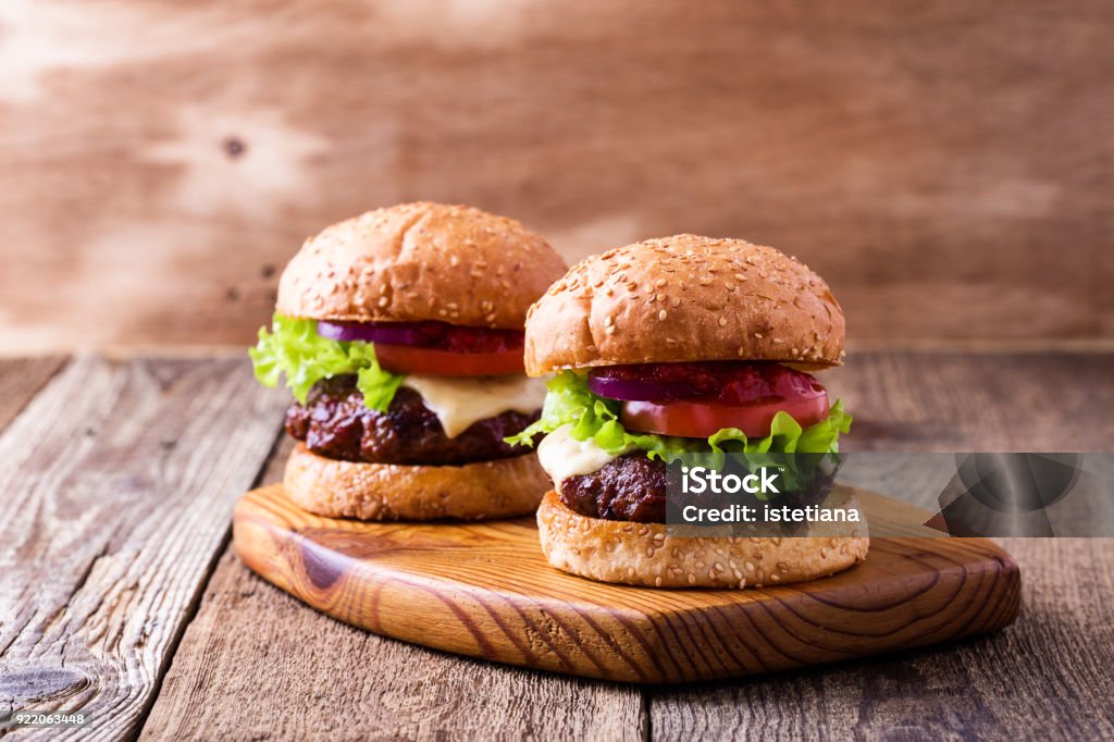 Deliciosa hamburguesa con lechuga, queso, tomate, cebolla roja - Foto de stock de Hamburguesa - Alimento libre de derechos