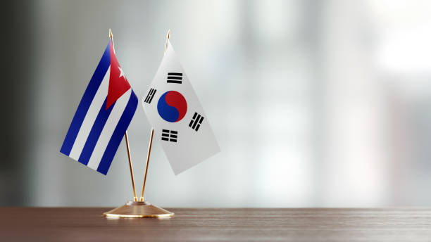 istock Cuban And South Korean Flag Pair On A Desk Over Defocused Background 922064126