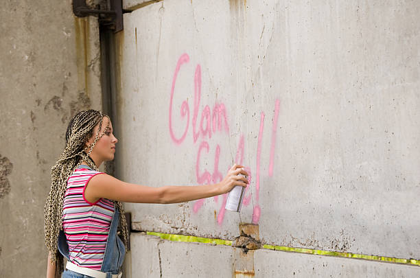 Young woman creating graffiti on the wall