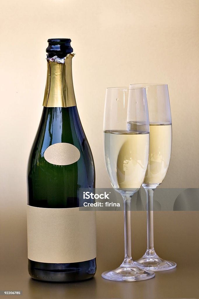 Close-up of champagne bottle and two flutes Bottle of champagne with gold blank label and two glasses Champagne Stock Photo