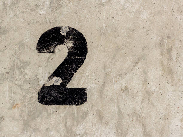 istock Number two 2 black painted on old rugged light grey concrete wall background 922077436
