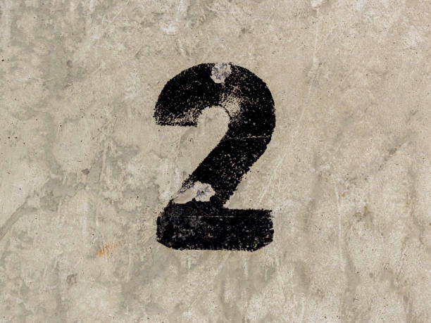 istock Number two 2 black painted on old rugged light grey concrete wall background 922077442