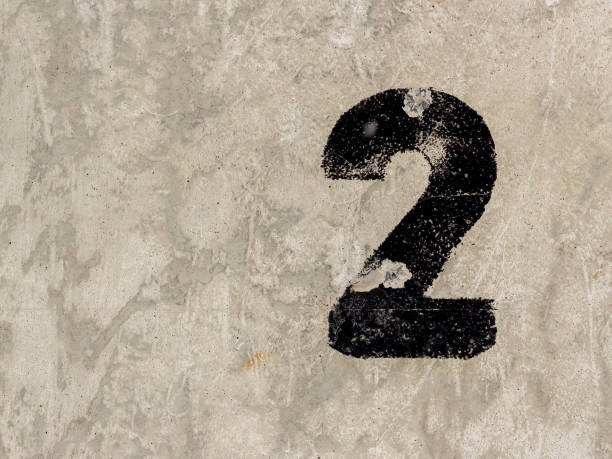 istock Number two 2 black painted on old rugged light grey concrete wall background 922077448
