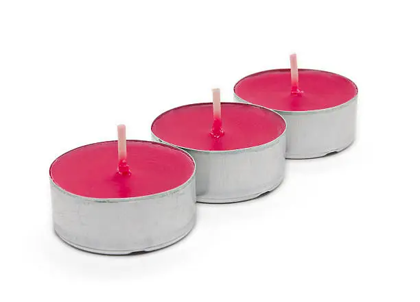 Three scented tealights with focus on the middle one. White background.