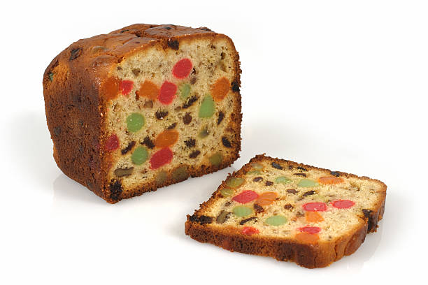 A Christmas fruit cake with one slice cut (XL) A freshly baked isolated loaf of candied Christmas fruitcake. fruitcake stock pictures, royalty-free photos & images