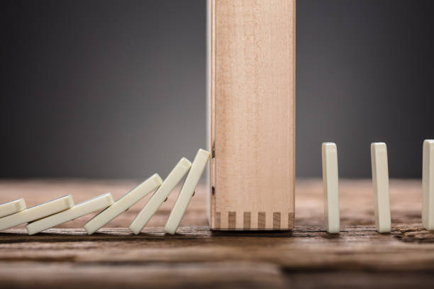 istock Wooden Block Amidst Falling And Upright Domino Pieces On Table 922088408