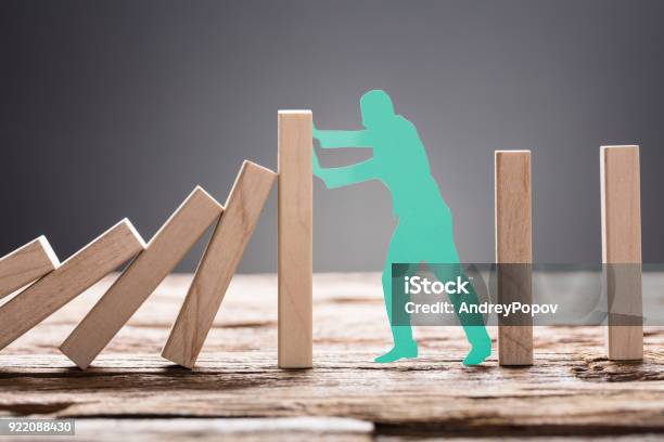 Green Paper Man Stopping Wooden Domino Blocks Stock Photo - Download Image Now - Responsibility, Crisis, Organization