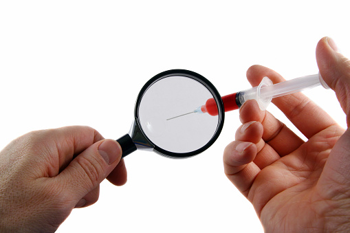 Looking through a magnifying lens to a syringe