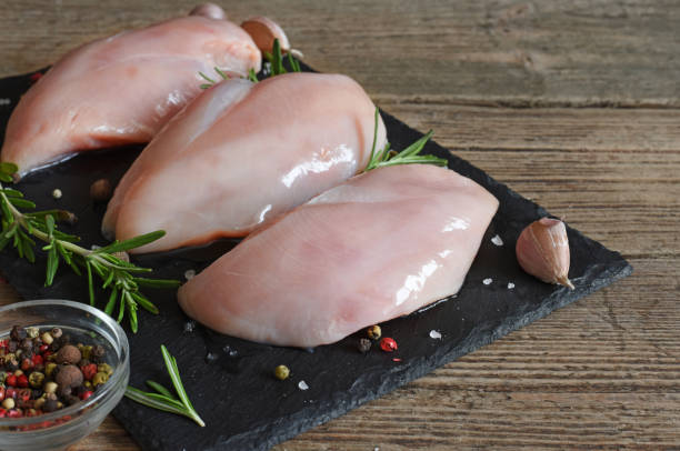 istock Raw chicken breasts witn rosemary and spices on black slate cutting board 922091364