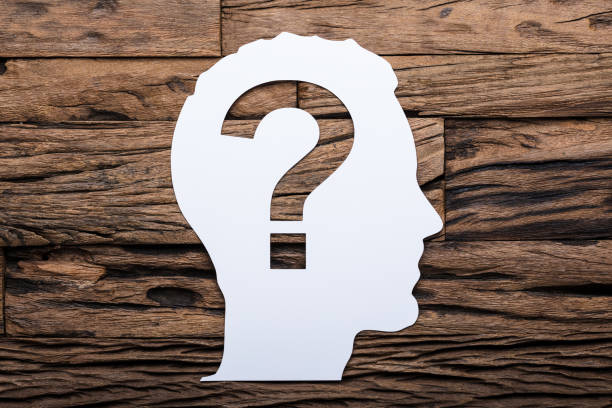 Directly above shot of paper businessman's head with question mark on wooden table