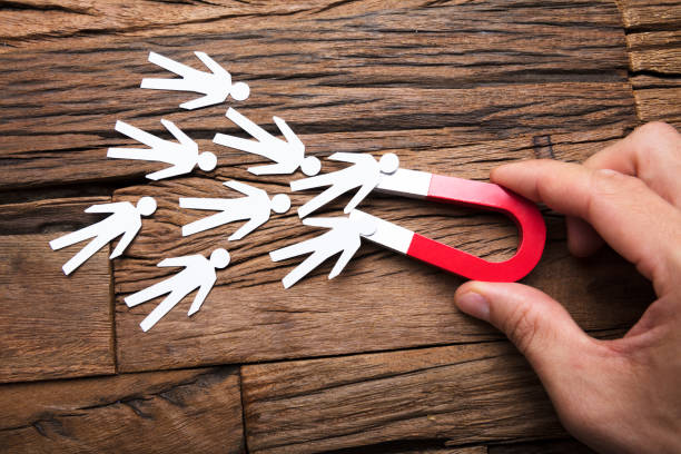 istock Businessman's Hand Holding Magnet Towards Papermen On Table 922106762