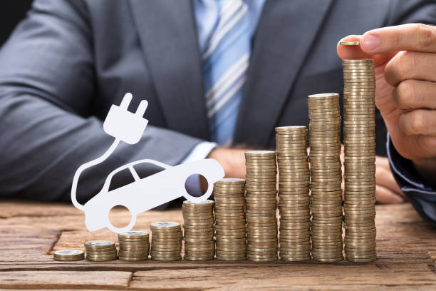 istock Businessman Stacking Coins With Electric Car At Table 922106772