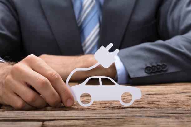 istock Businessman Holding Paper Electric Car At Table 922106854